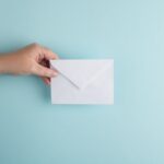 Pisanie newsletterów - grafika do tekstu. Na obrazku: dłoń trzymająca kopertę. Autor: Erica Steeves, źródło: Unsplash.