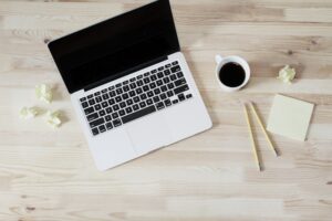 Tekst na landing page - grafika do tekstu. Na obrazku: laptop, kubek, notes i ołówki. Autor: Lauren Mancke, źródło: Unsplash.