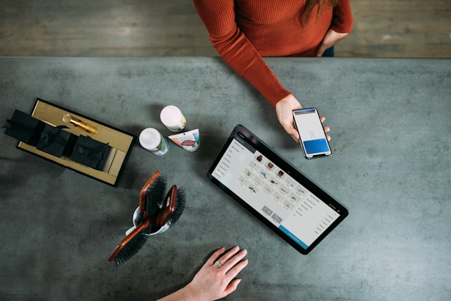 Jak stworzyć stronę przyjazną klientom? - grafika do tekstu. Na obrazku: akcesoria salonu fryzjerskiego oraz osoby przeglądające smartfon i notebook. Autor: Blake Wisz , źródło: Unsplash.