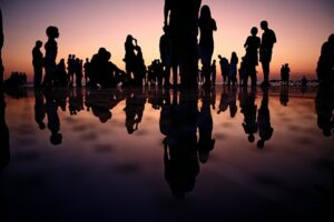 Jak pisać do grupy docelowej? - grafika do tekstu. Na obrazku: ludzie obserwujący zachód słońca. Autor: Mario Purisic, źródło: Unsplash.