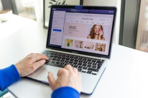 Błędy w tekstach sprzedażowych - grafika do tekstu. Na obrazku: osoba przeglądająca ofertę z branży beauty na laptopie. Autor: Shoper AF, źródło: Unsplash.